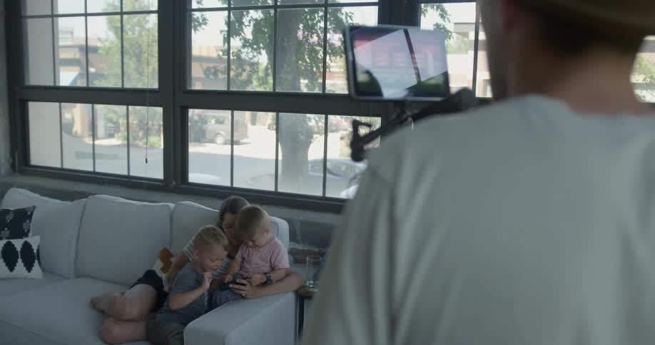 A man photographs his wife and sons sitting on the couch