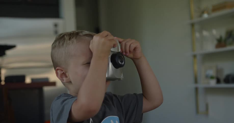 A boy holds a camera up as if taking a photo