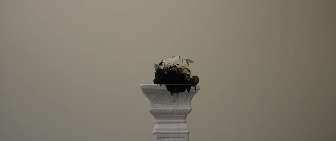 Black ink drips down a pedestal from a painted rose