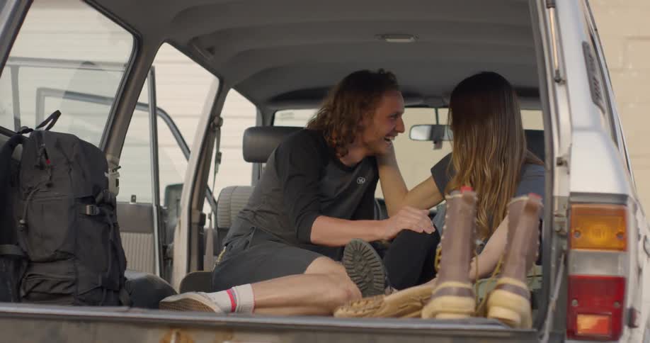 A man and woman flirt in the back of a parked truck