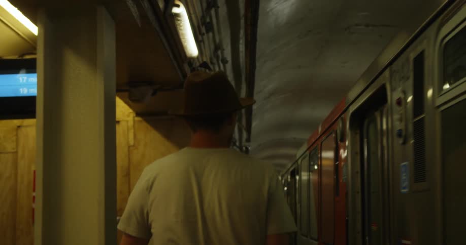 Man walks on a subway platform next to a moving subway