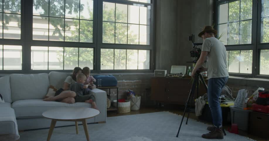 A man photographs a mom and two boys on a sofa