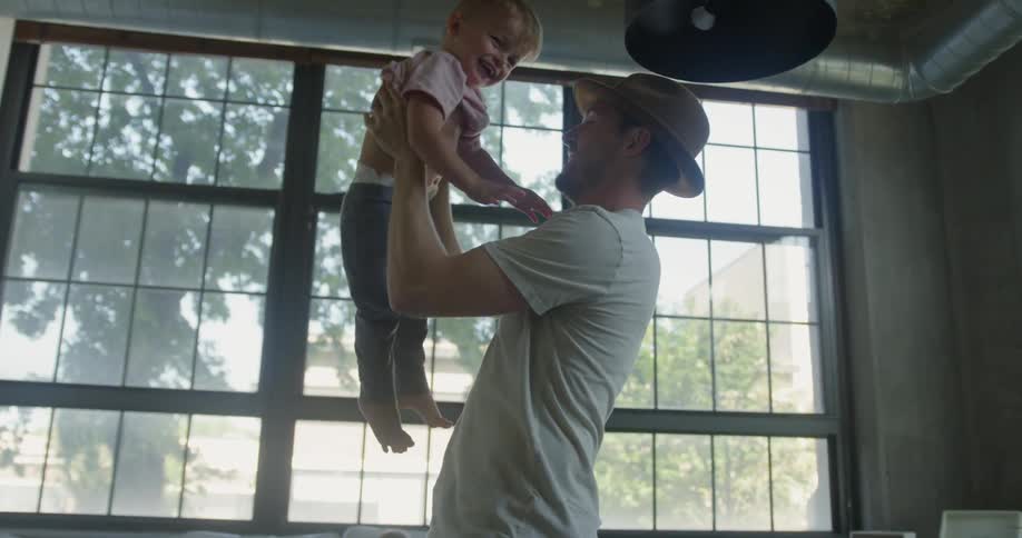 A man picks up a child near a window