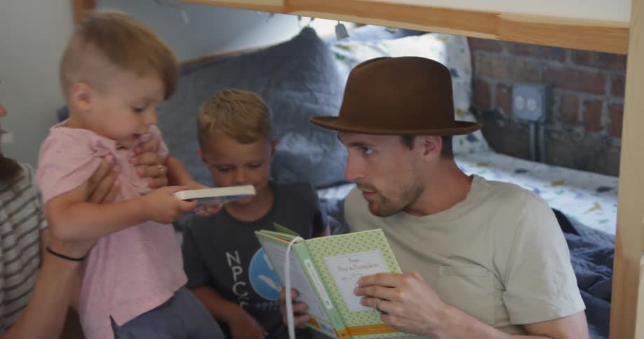Woman and man read a book to two boys