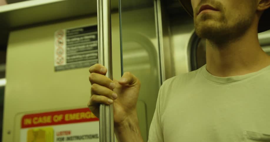 Man holds onto a pole as he rides in the train