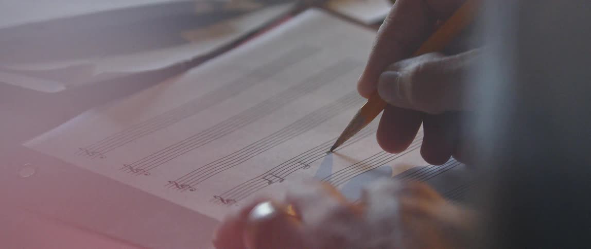 The person is writing musical notes in a book