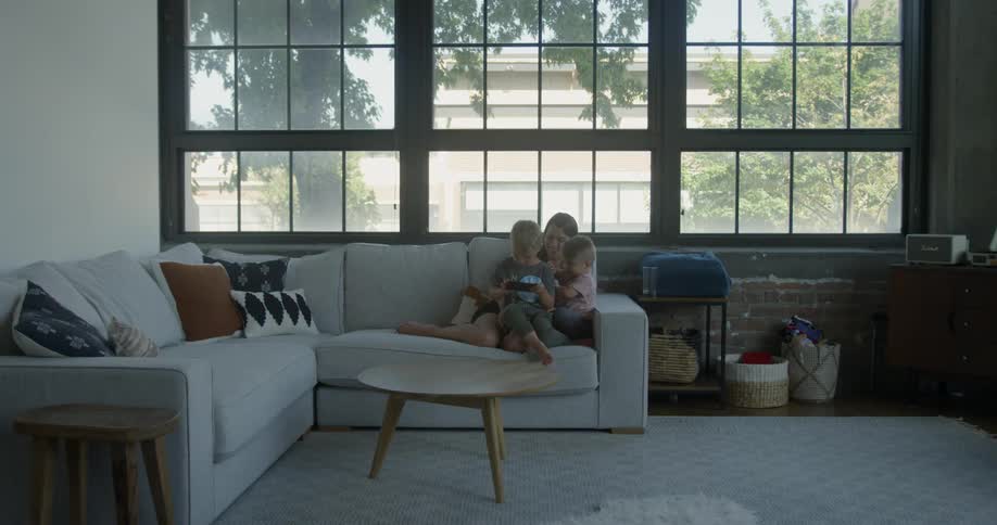 Woman sits on the sofa with two small children
