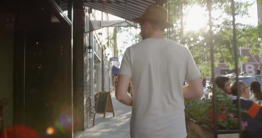 Man walks on the sidewalk next to buildings on a sunny day