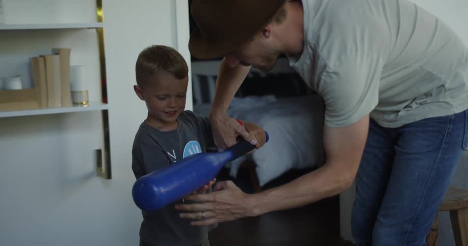 A dad shows his son how to hold a plastic bat