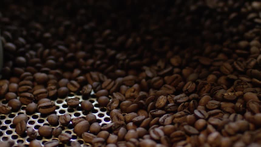 A large amount of coffee beans being turned in a machine