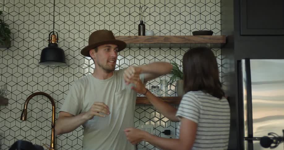 Man and woman dance in the kitchen as they laugh