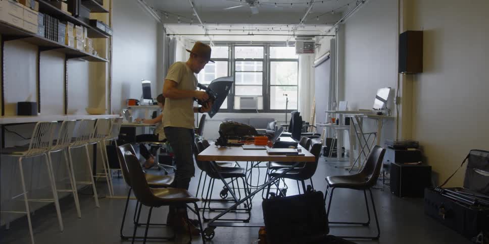 A man stands at a table and adjusts camera equipment