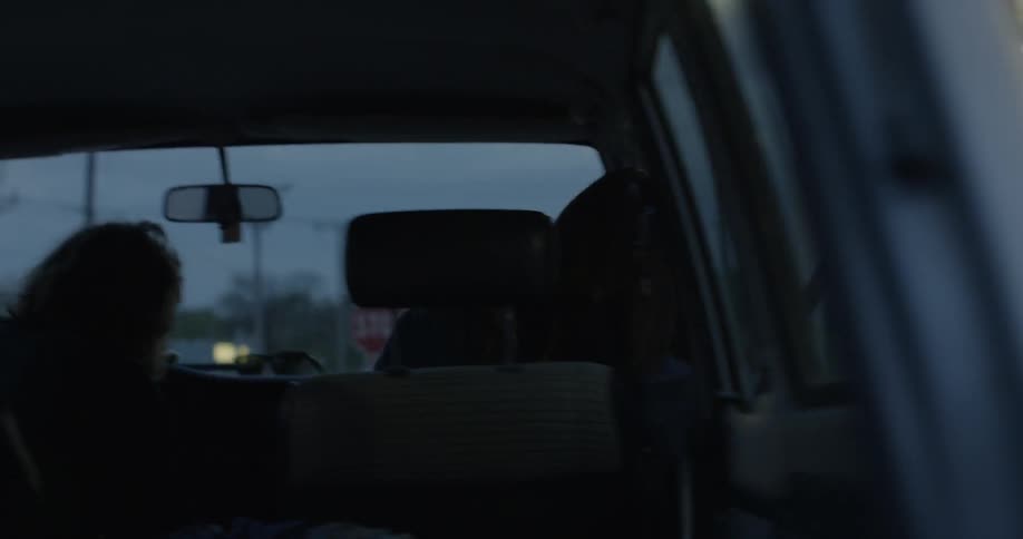 A woman climbs into the passenger seat of a car