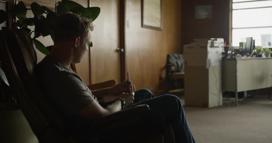 A man writes while sitting in an office