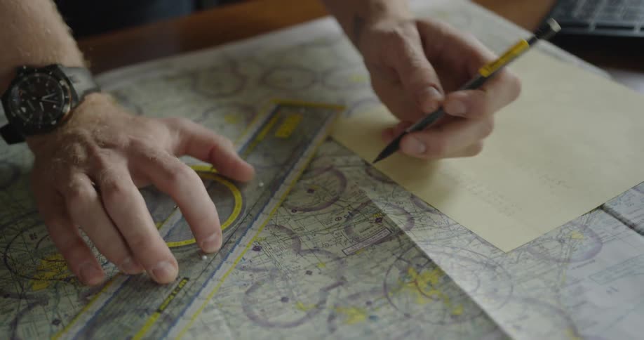 A man holds a ruler and draws lines on a map