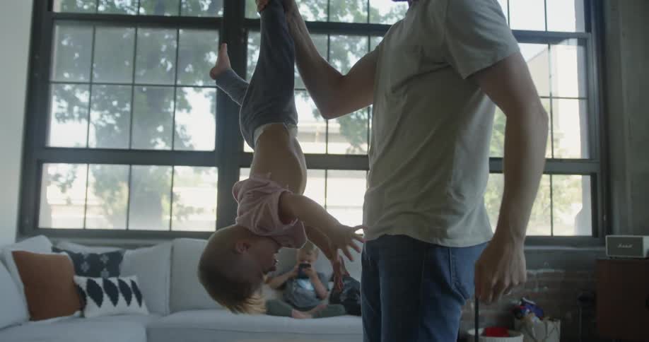 A dad holds his child upside down