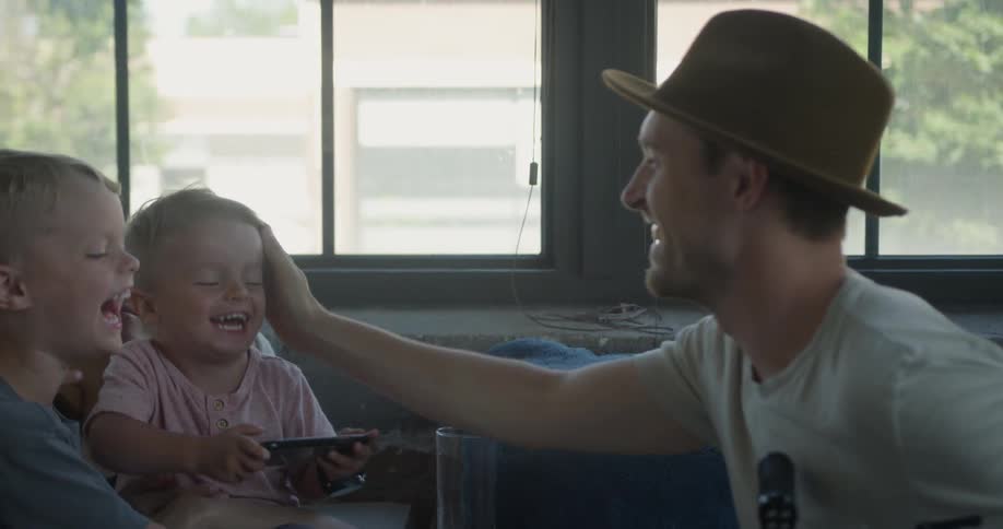 A man smiles as he touches his laughing son