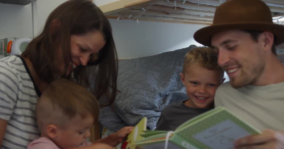 A couple laughs as a dad reads to their kids