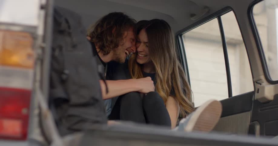 A man and woman cuddle in the back of a truck