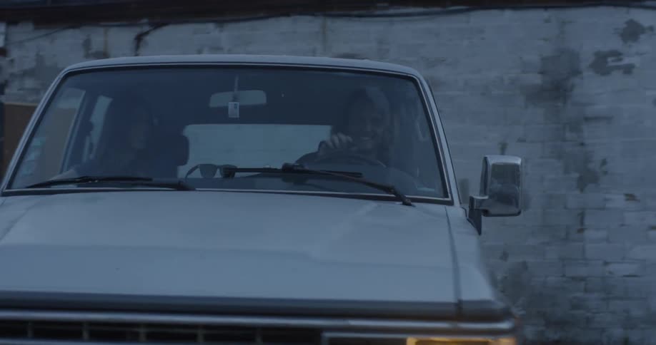 A man and woman ride in an old truck