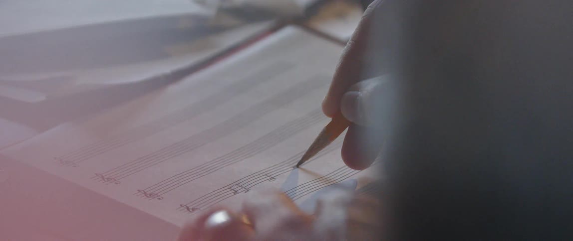 A composer writes music notes on a music sheet
