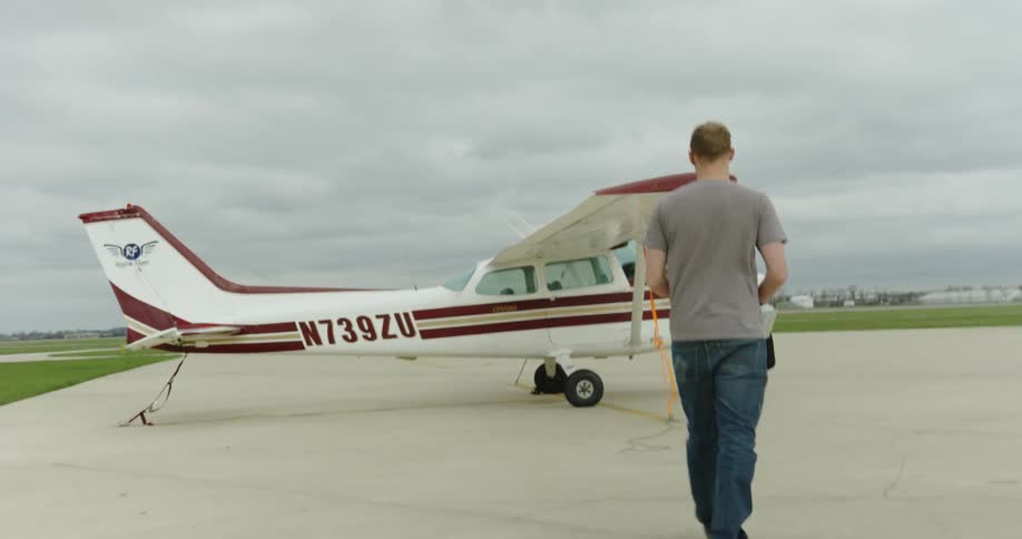A man walks towards a small airplane on a tarmac
