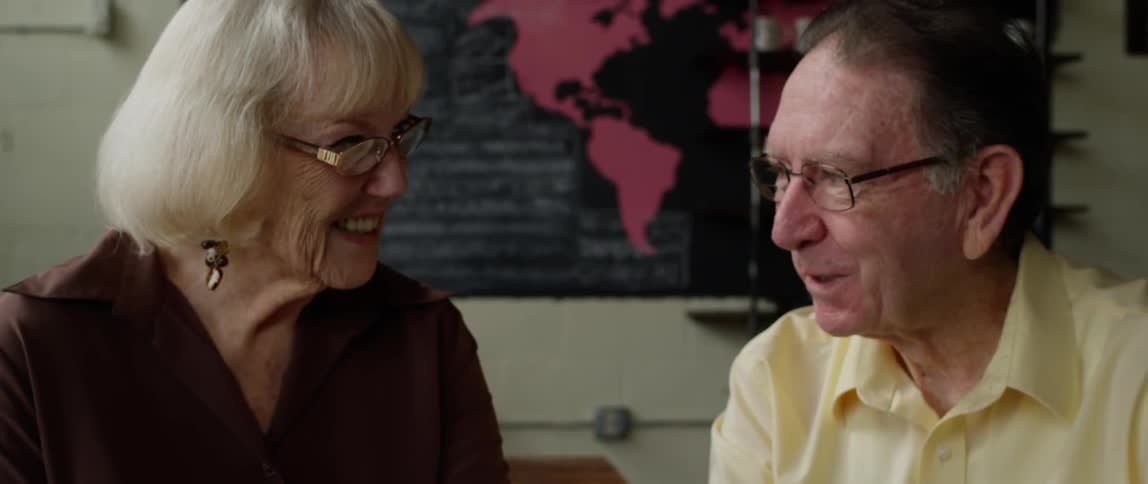 An elderly couple chatting at a coffee shop