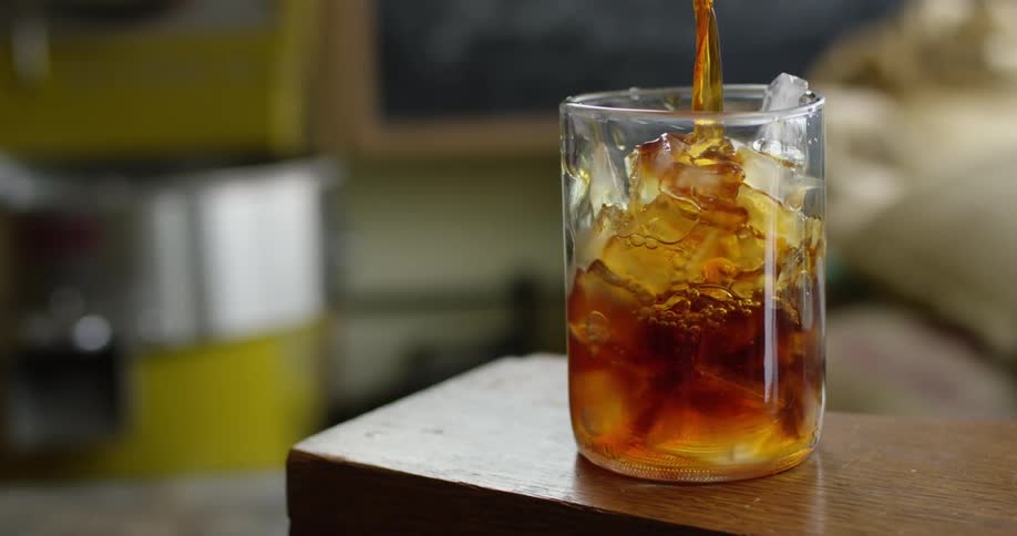 A glass filled with ice cubes is filled with liquid