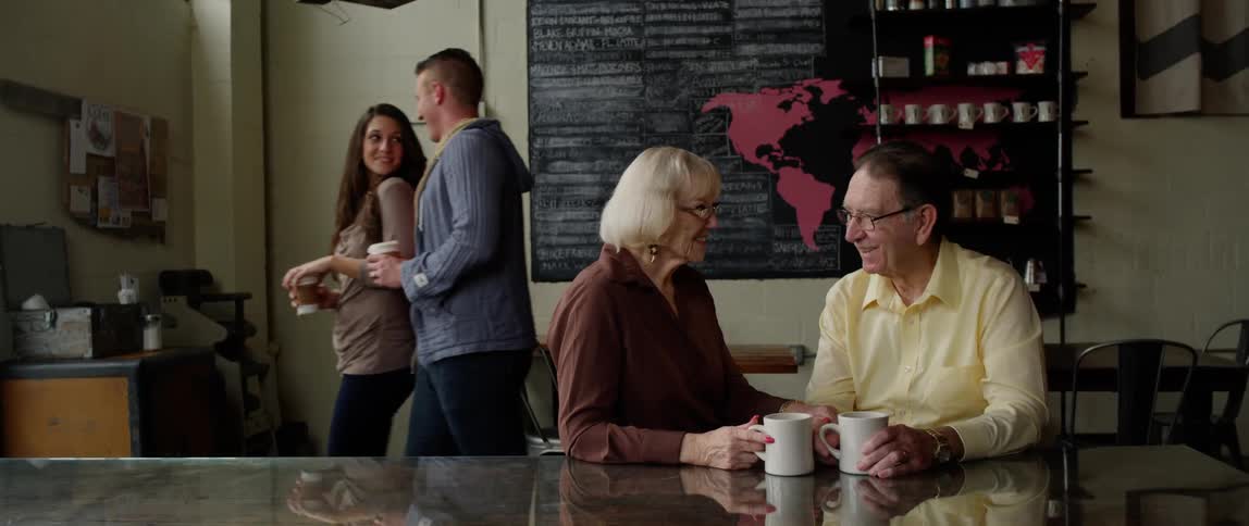 A man and woman enjoy a cup of coffee while sitting at a table in a cafe