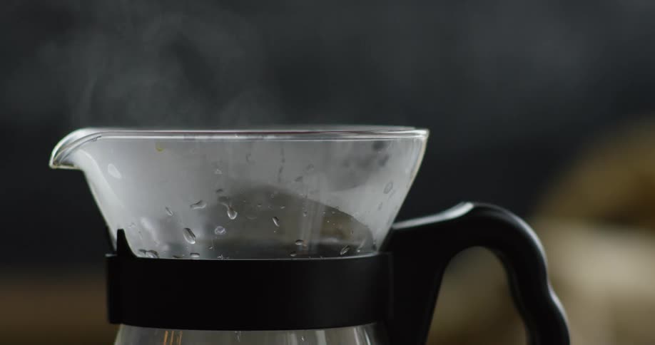 Water being poured into a glass pitcher with steam rising from it