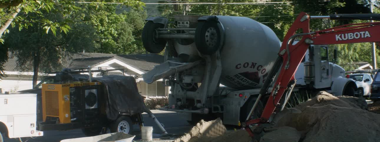 A cement truck backs up in the yard
