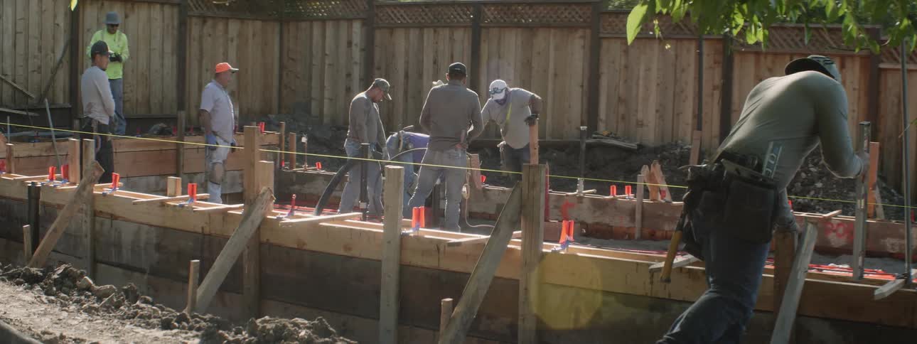 Men work at a construction site in a backyard