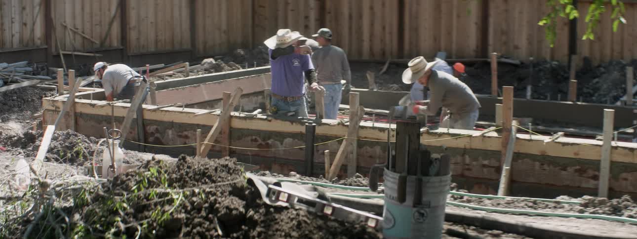 Men work on pulling boards off a poured cement wall