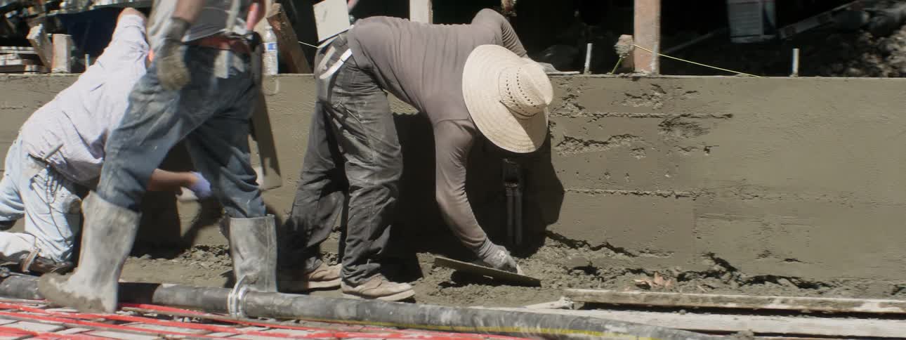 Workers smooth concrete at a construction site