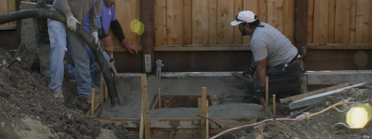 Workers lay concrete at a construction site