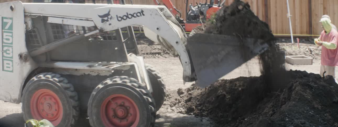 A bulldozer digs up dirt in a backyard