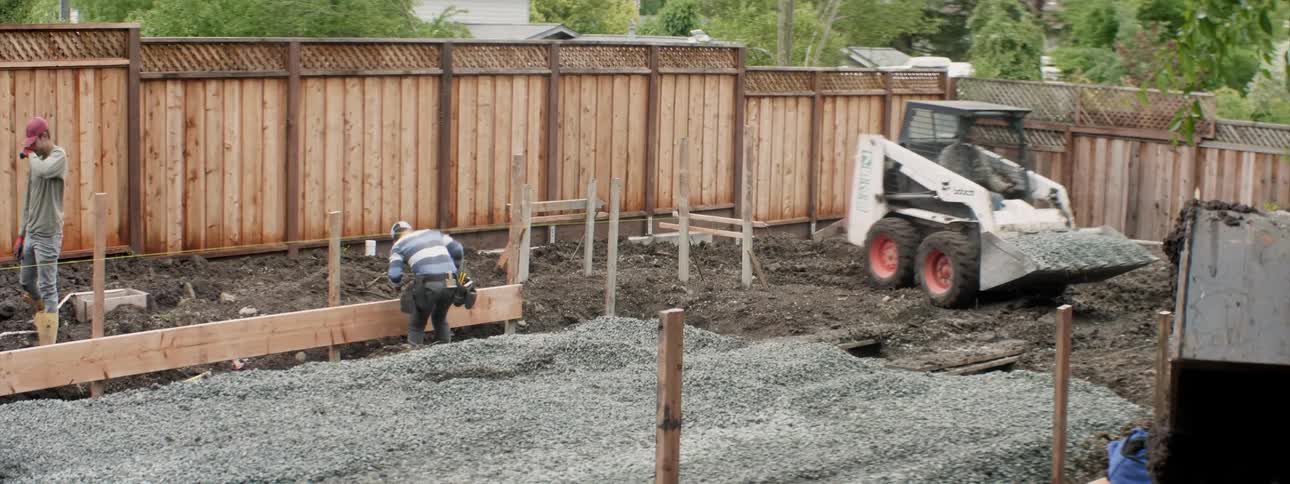 The bulldozer drives around the worker in the yard