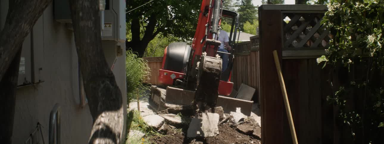 An excavator tears out concrete at a construction site