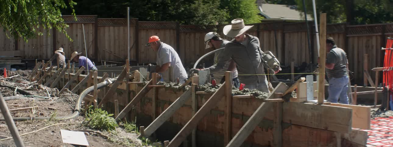 Several men work on the foundation of a building
