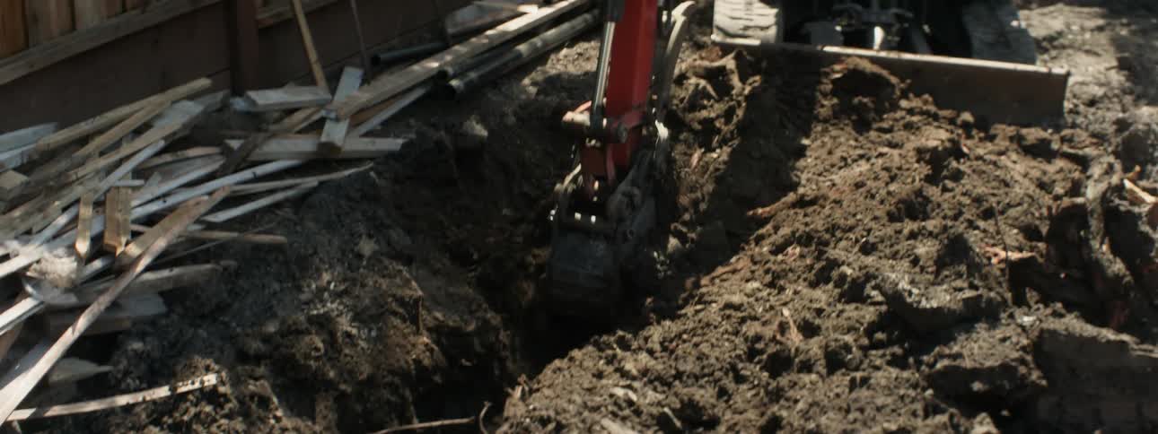 The man digs a trench in the yard
