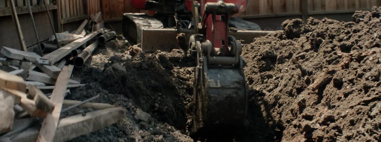 An excavator digs up dirt in a backyard