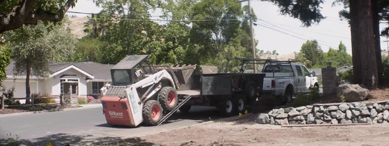 Bobcat drives up a ramp and into a large trailer