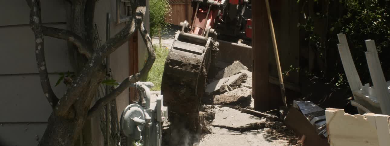 An excavator tears out concrete at a construction site