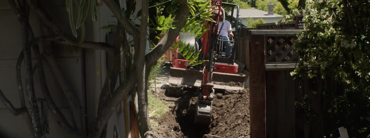 An excavator digs up dirt in a backyard
