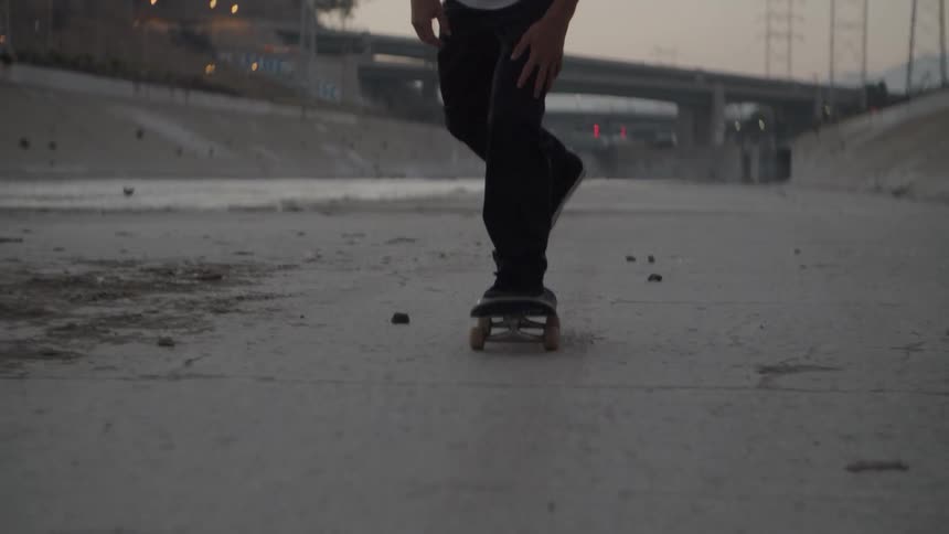 A man skateboards in a city at sunset