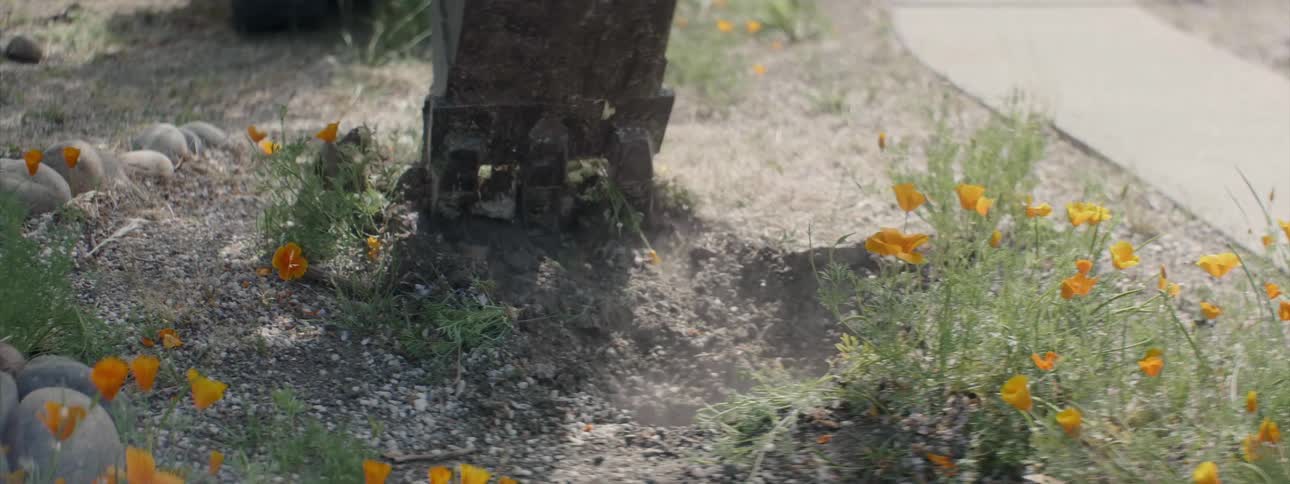 The construction vehicle digs up the soil of the flower bed