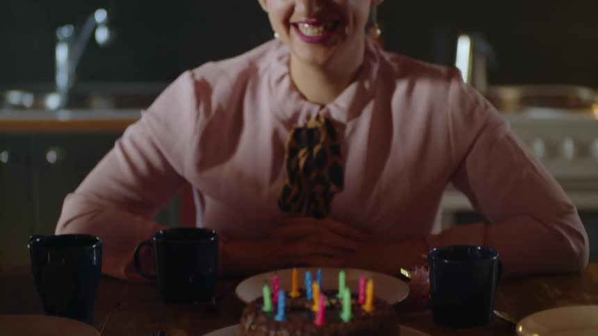A woman blows out birthday candles on a cake