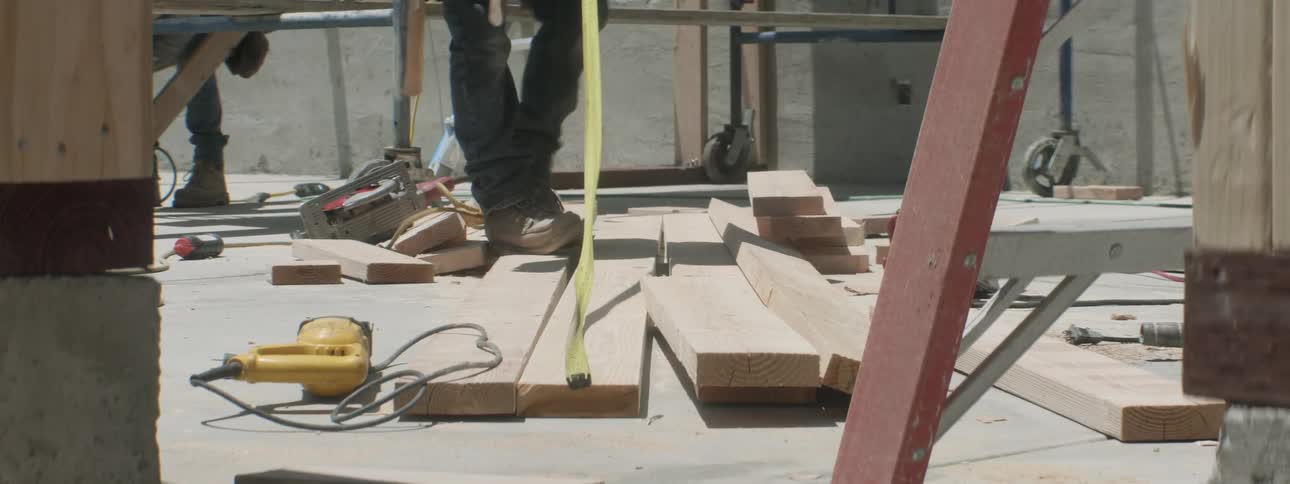 A construction worker measures a piece of wood