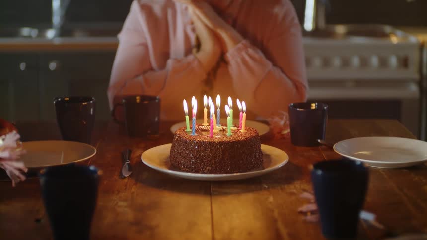 The woman brings a birthday cake to the table