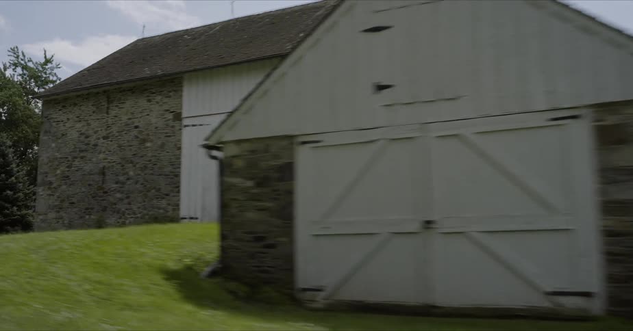 A car travels by a stone building in the countryside